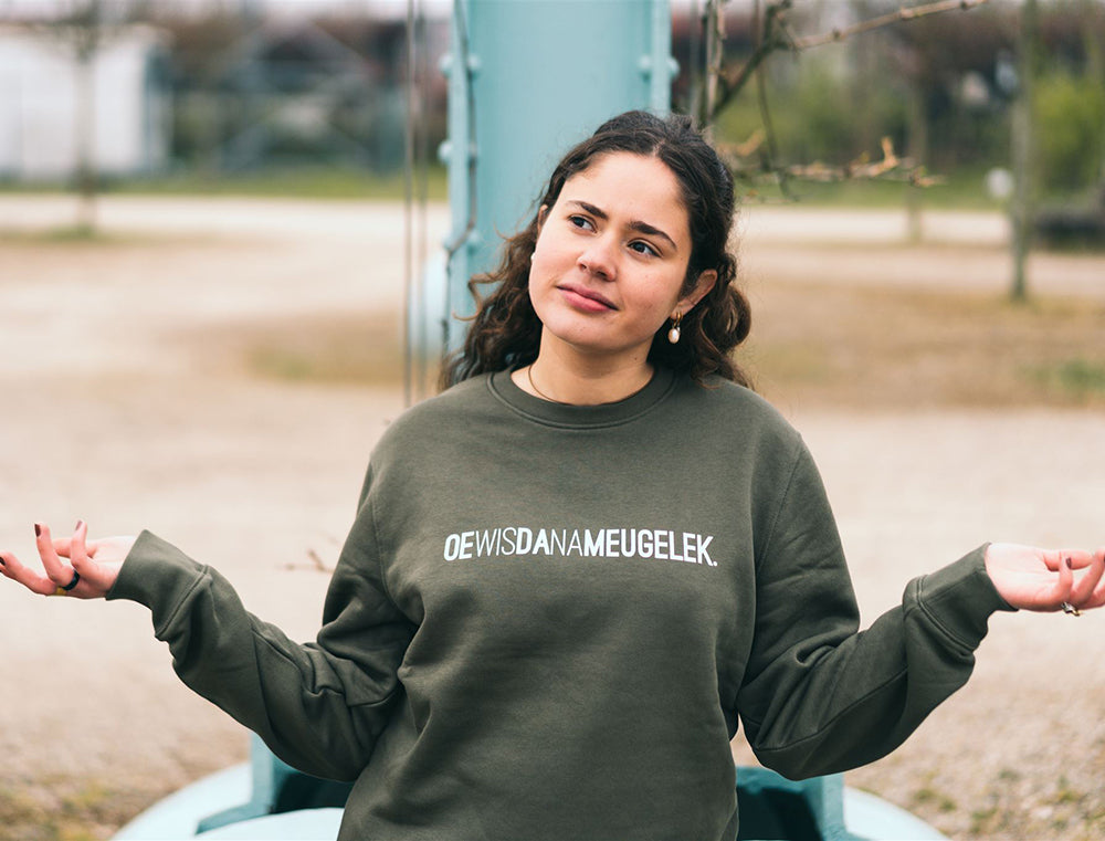 Vrouw met kaki trui met opdruk OEWISDANAMEUGELEK.