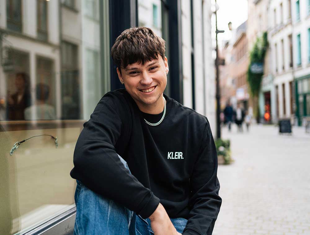 Man met een zwarte sweater met opdruk KLEIR.