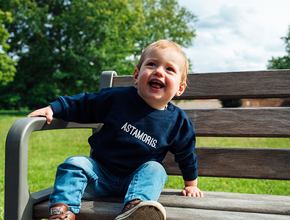 Baby met donkerblauwe sweater met opdruk ASTAMORIS.