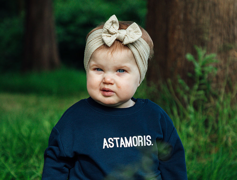 Baby met donkerblauwe sweater met opdruk ASTAMORIS.