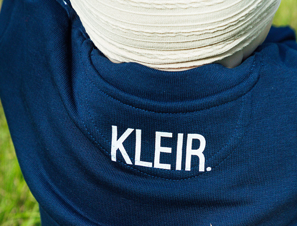 Close-up van donkerblauwe sweater met opdruk KLEIR. op de achterkant
