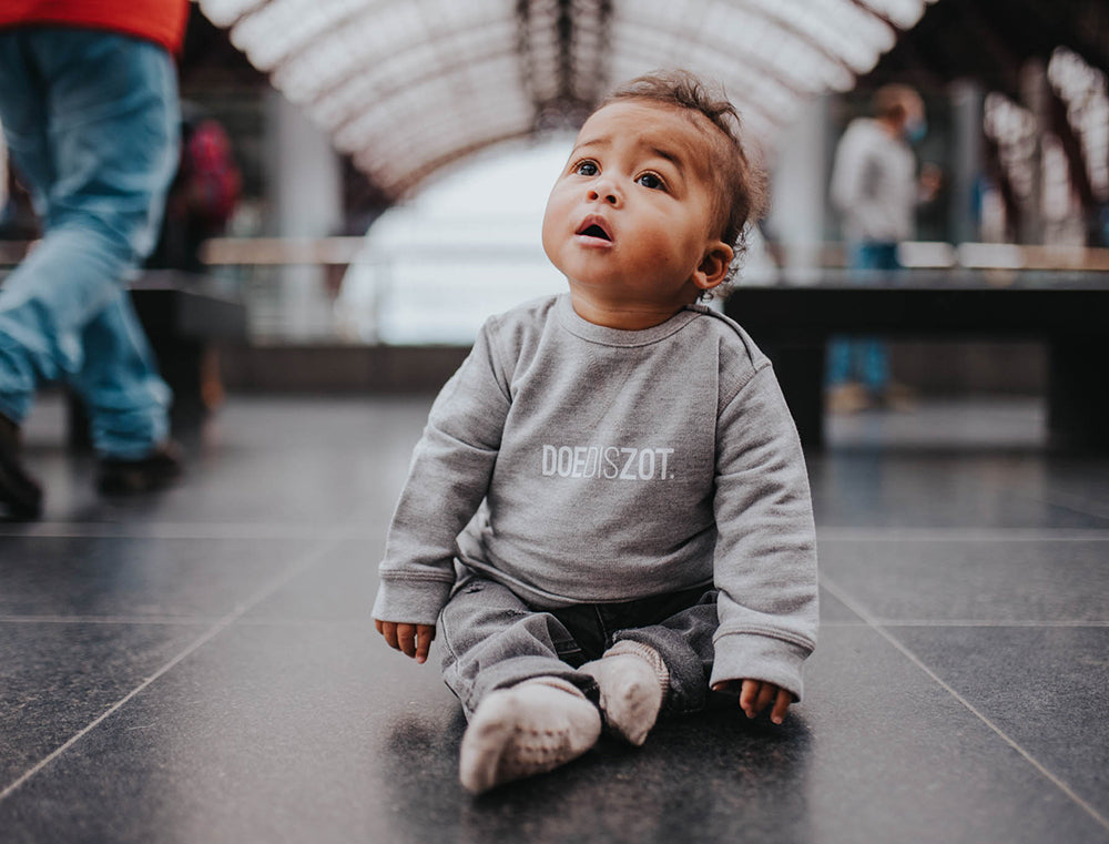 Baby met grijze trui met opdruk DOEDISZOT.
