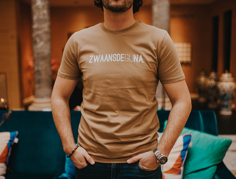Close-up van een bruine T-shirt met opdruk ZWAANSDEGIJNA.