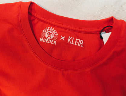 Close-up van logo's Discobaar A moeder x KLEIR. in een rode T-shirt
