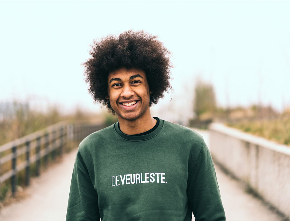 Man met een groene trui met opdruk DEVEURLESTE.