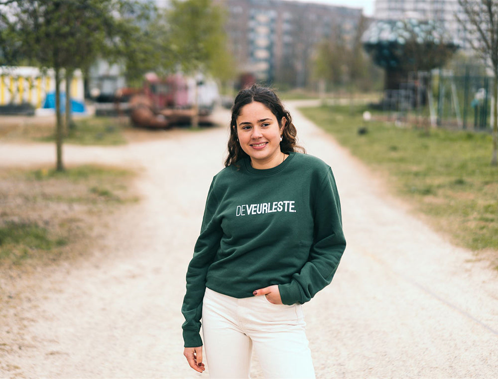 Vrouw met een groene trui met opdruk DEVEURLESTE.