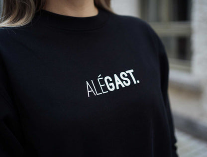 Close-up van een zwarte sweater met opdruk ALEGAST.