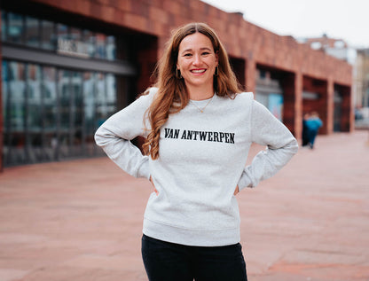 Vrouw met een grijze trui met opdruk 'VAN ANTWERPEN'