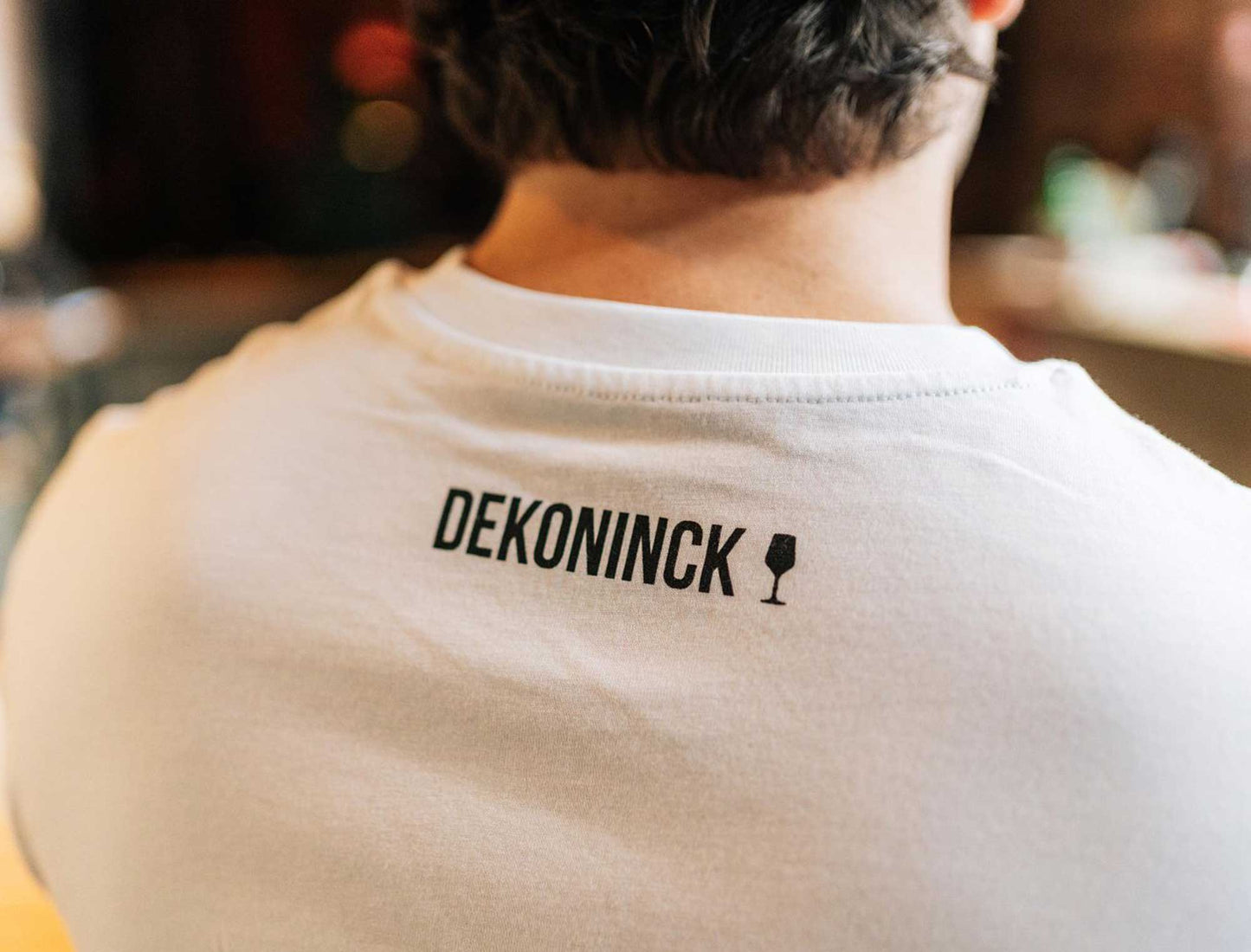 Close-up van de achterkant van een witte T-shirt met het logo van De Koninck.