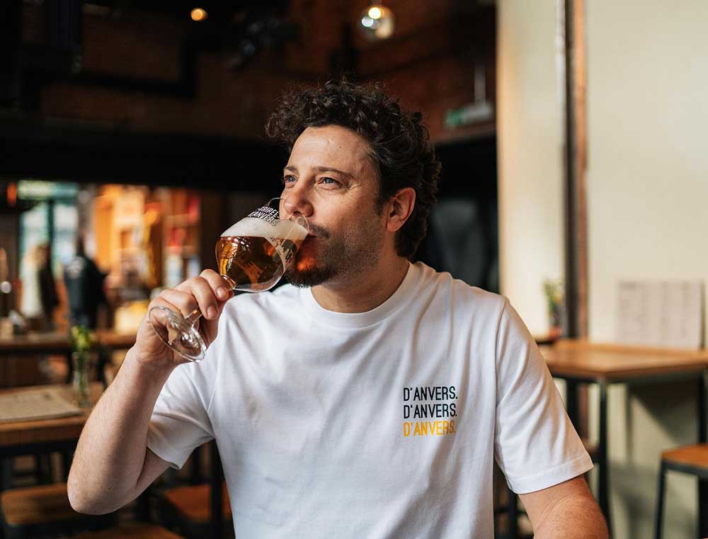 Man met een witte T-shirt met opdruk d'ANVERS.