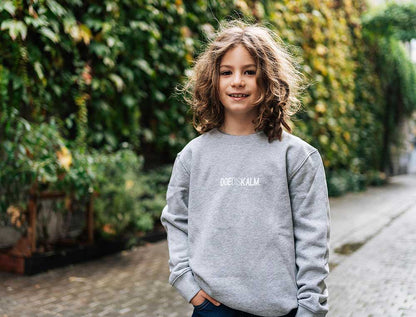 Jongen met een grijze sweater met opdruk DOEDISKALM. voor kinderen