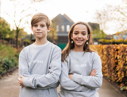Jongen en meisje met een grijze sweater met opdruk DOEDISKALM. voor kinderen