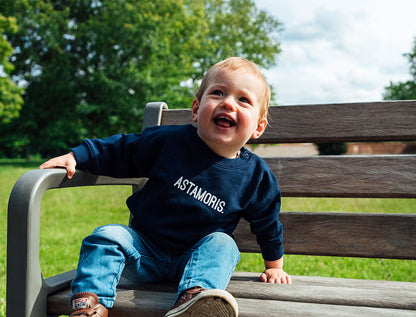 Baby met donkerblauwe sweater met opdruk ASTAMORIS.