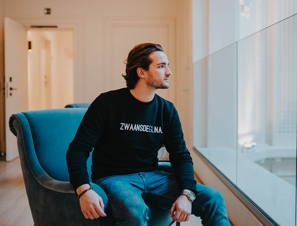 Man met zwarte trui met opschrift 'ZWAANSDEGIJNA.'