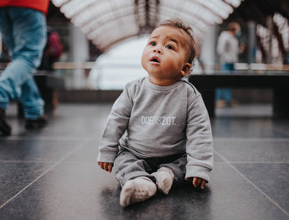 Baby met grijze trui met opdruk DOEDISZOT.