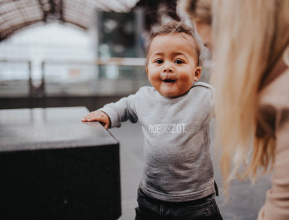 Baby met grijze trui met opdruk DOEDISZOT.