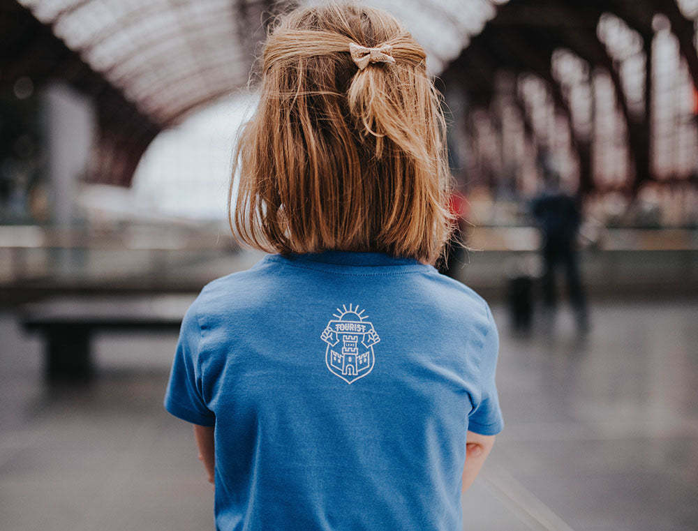 Close-up van het logo van Tourist op een blauwe T-shirt.
