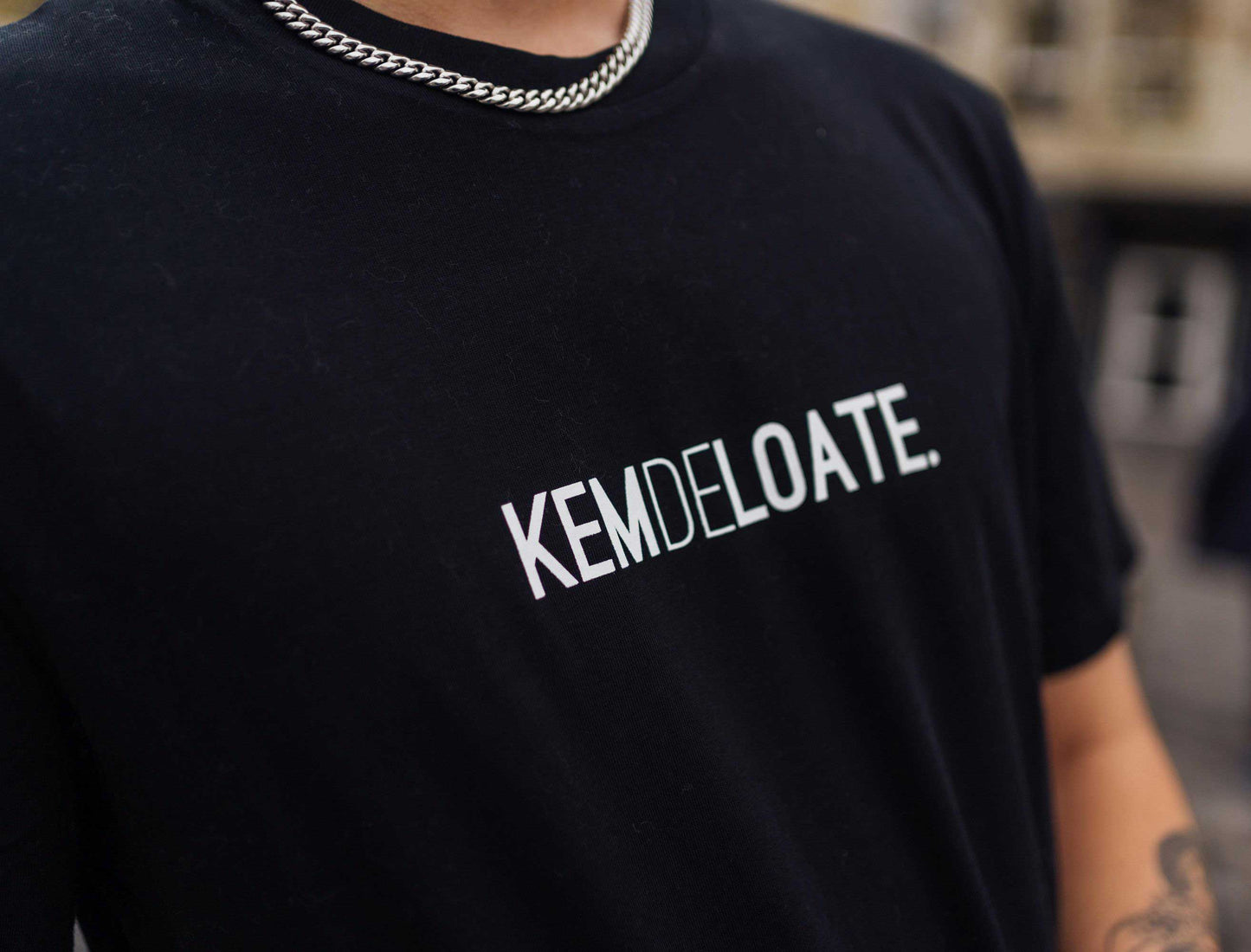 Close-up van een zwarte T-shirt met opdruk KEMDELOATE.