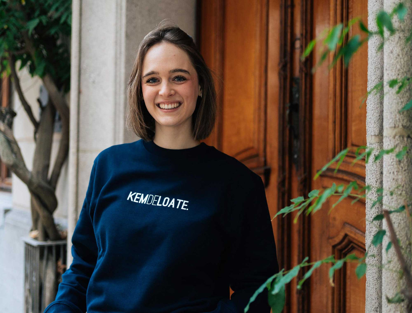 Vrouw met een donkerblauwe sweater met opdruk KEMDELOATE.