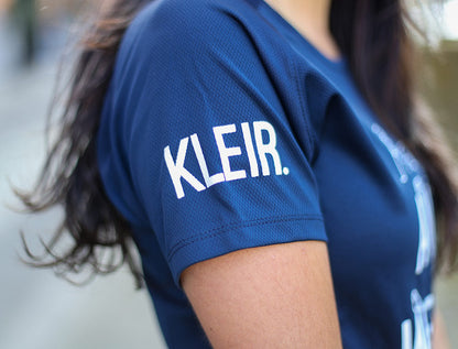 Close-up van een blauwe mouw met opdruk KLEIR.
