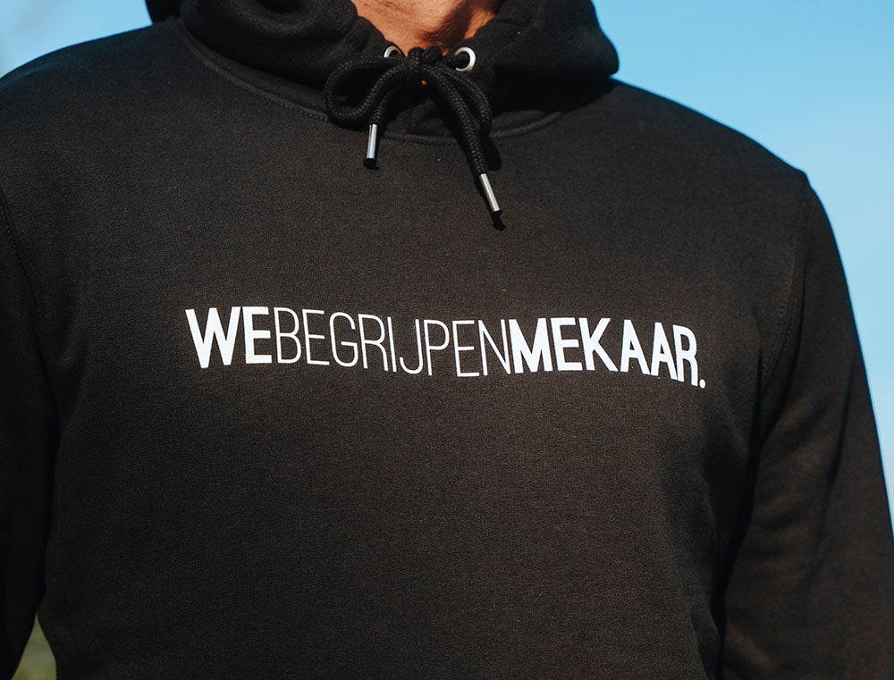 Close-up van zwarte hoodie met opdruk WEBEGRIJPENMEKAAR.