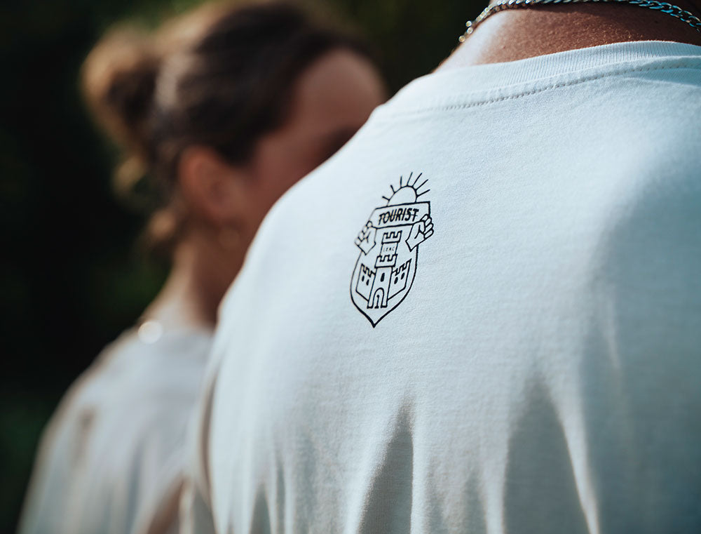 Close-up van achterkant witte T-shirt met logo TOURIST.