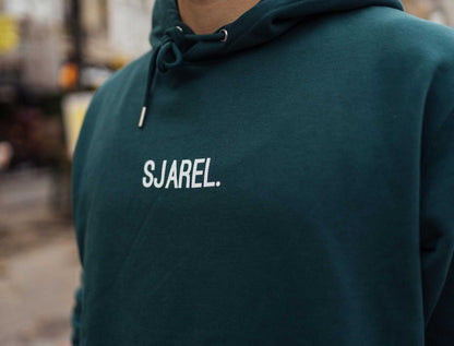 Close-up van een groene hoodie met opdruk SJAREL.