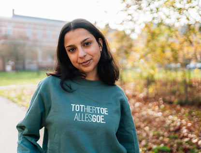 Vrouw met een groene trui met opdruk TOTHIERTOEALLESGOE.