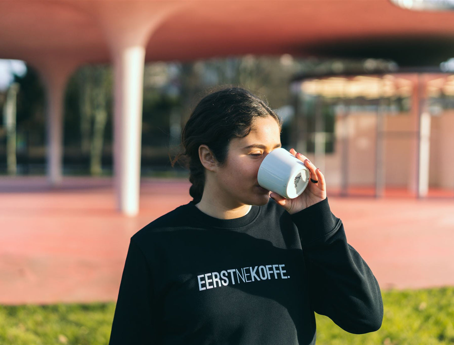 Vrouw met een zwarte trui met opdruk EERSTNEKOFFE.