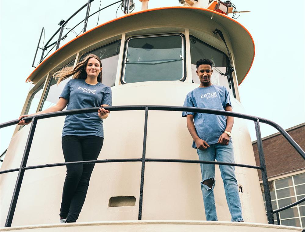 Man en vrouw op een schip met blauwe T-shirt met opdruk KAPITEINVANTSTAD.