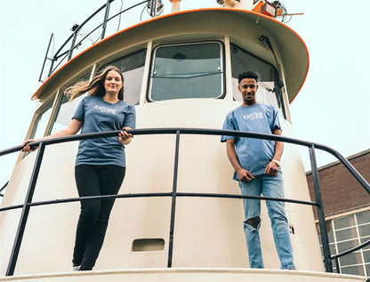 Man en vrouw op een schip met blauwe T-shirt met opdruk KAPITEINVANTSTAD.