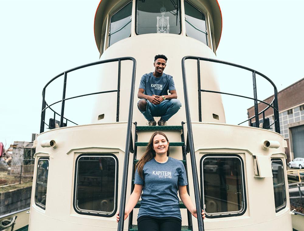 Man en vrouw op een schip met blauwe T-shirt met opdruk KAPITEINVANTSTAD.