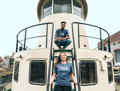 Man en vrouw op een schip met blauwe T-shirt met opdruk KAPITEINVANTSTAD.