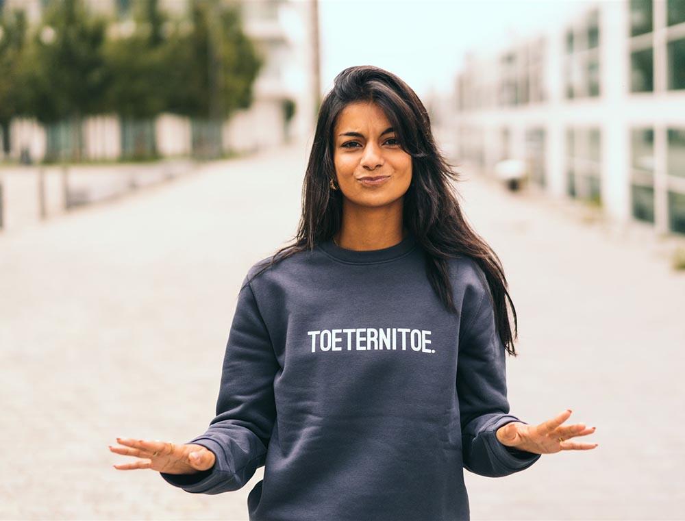 Vrouw met grijze trui met opdruk TOETERNITOE.