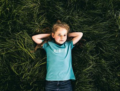 Meisje met groene T-shirt met opdruk KLEIRVEUR.
