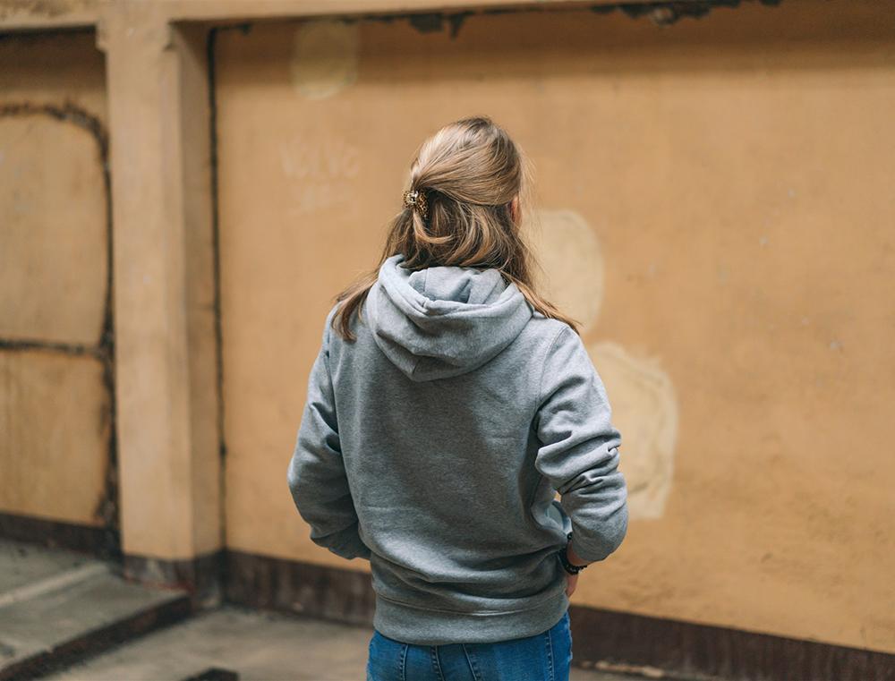 Achteraanzicht van vrouw met grijze hoodie.