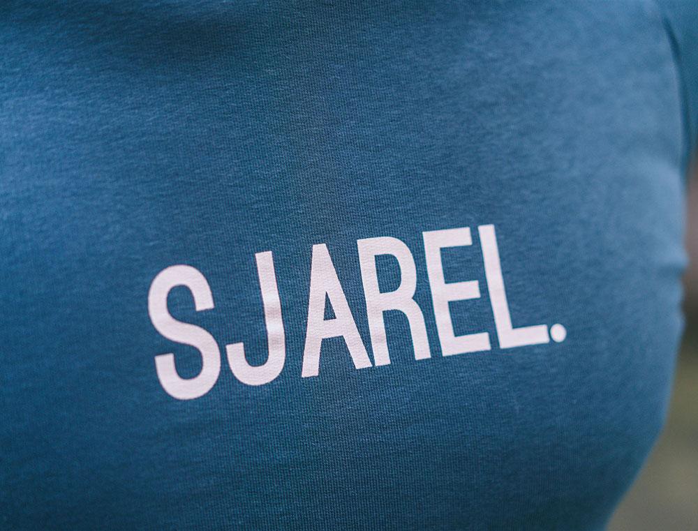 Close-up van blauwe trui met opdruk SJAREL.