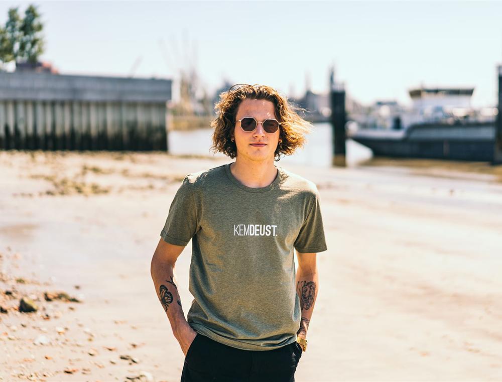 Man met kaki T-shirt met opdruk KEMDEUST.