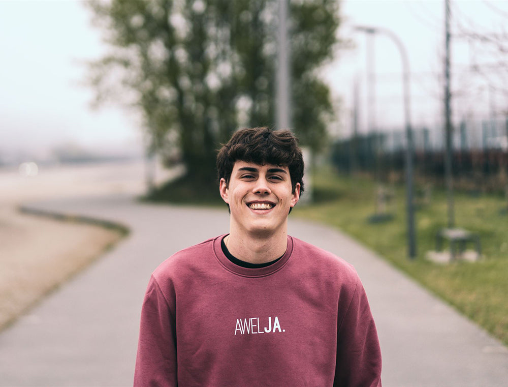 Man met bordeaux trui met opdruk AWELJA.
