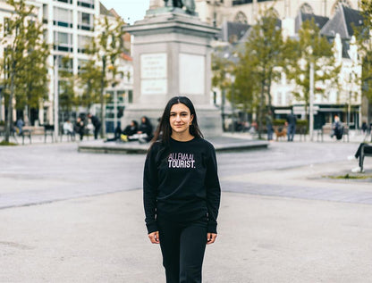Vrouw met zwarte trui met opdruk 'ALLEMAALTOURIST.'