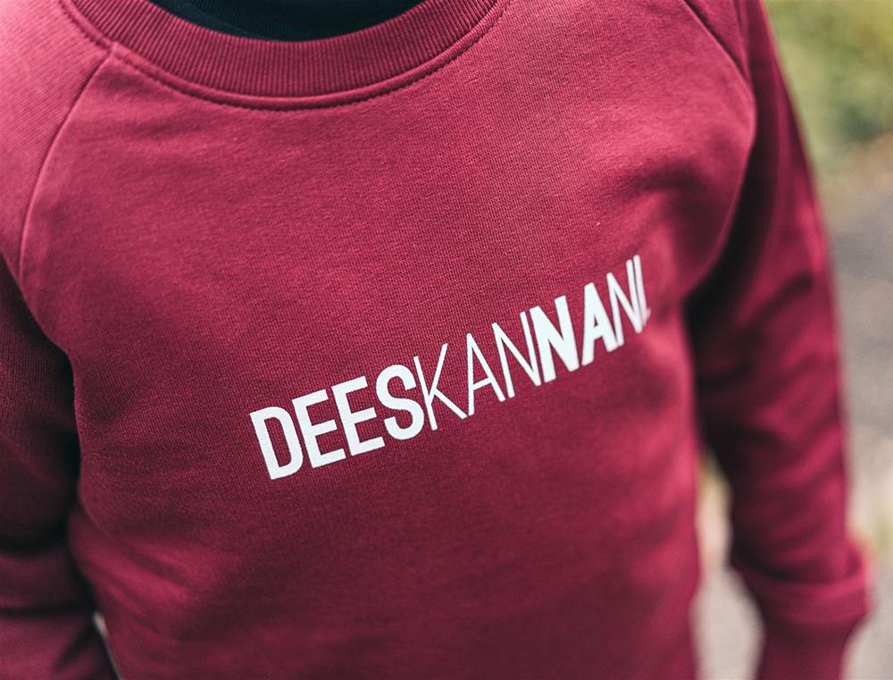 Close-up van bordeaux trui met opdruk DEESKANNANI.