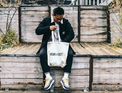 Man met totebag met opdruk VEURWADIST.