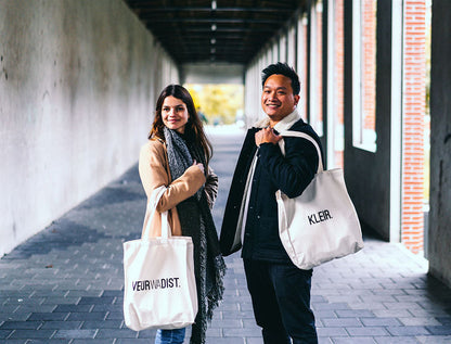 Man en vrouw met totebag met opdruk VEURWADIST. en KLEIR.