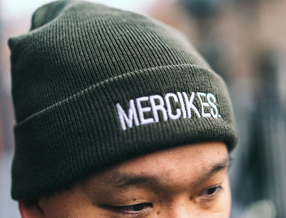 Close-up van een groene muts met opdruk MERCIKES.