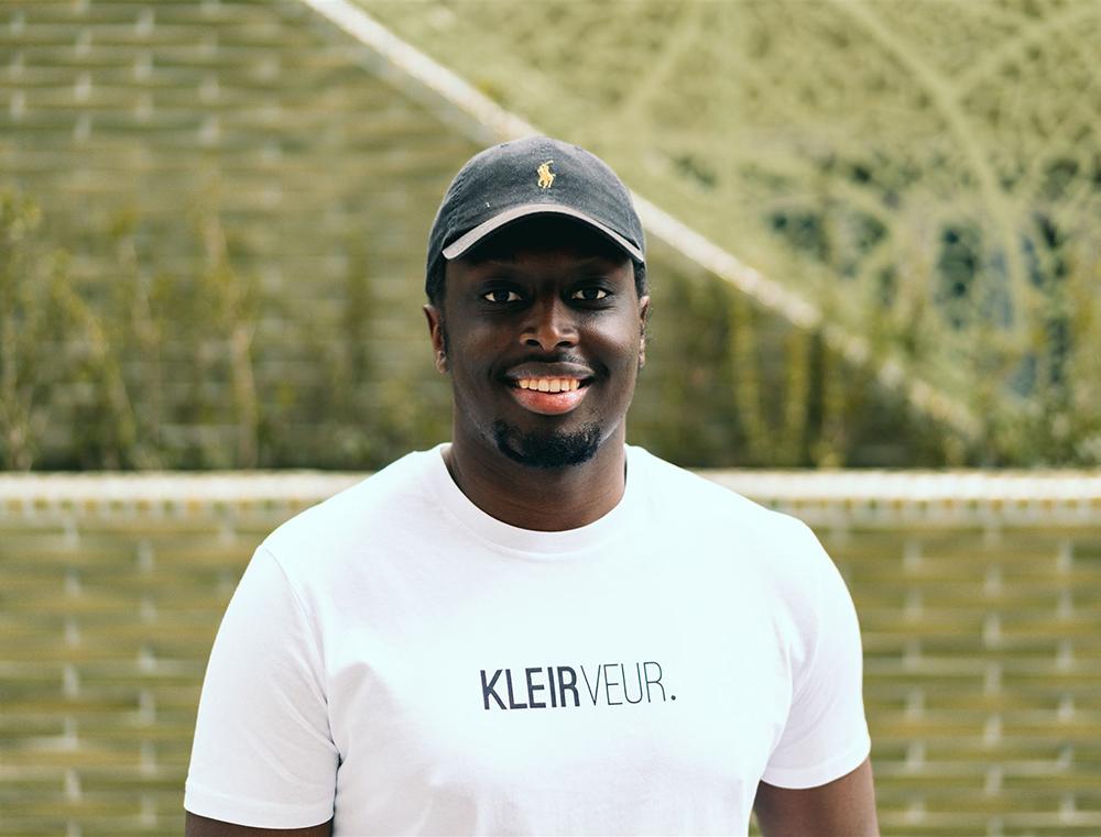 Man met witte T-shirt met opdruk 'KLEIRVEUR.'