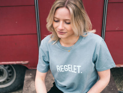 Vrouw met lichtblauwe T-shirt met opdruk REGELET.
