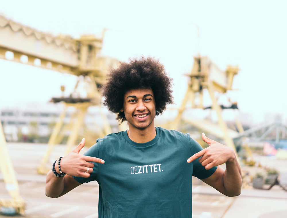 Man met petrolblauwe T-shirt met opdruk OEZITTET.