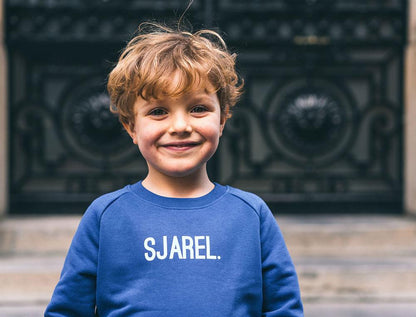 Jongen met blauwe trui met opdruk SJAREL.