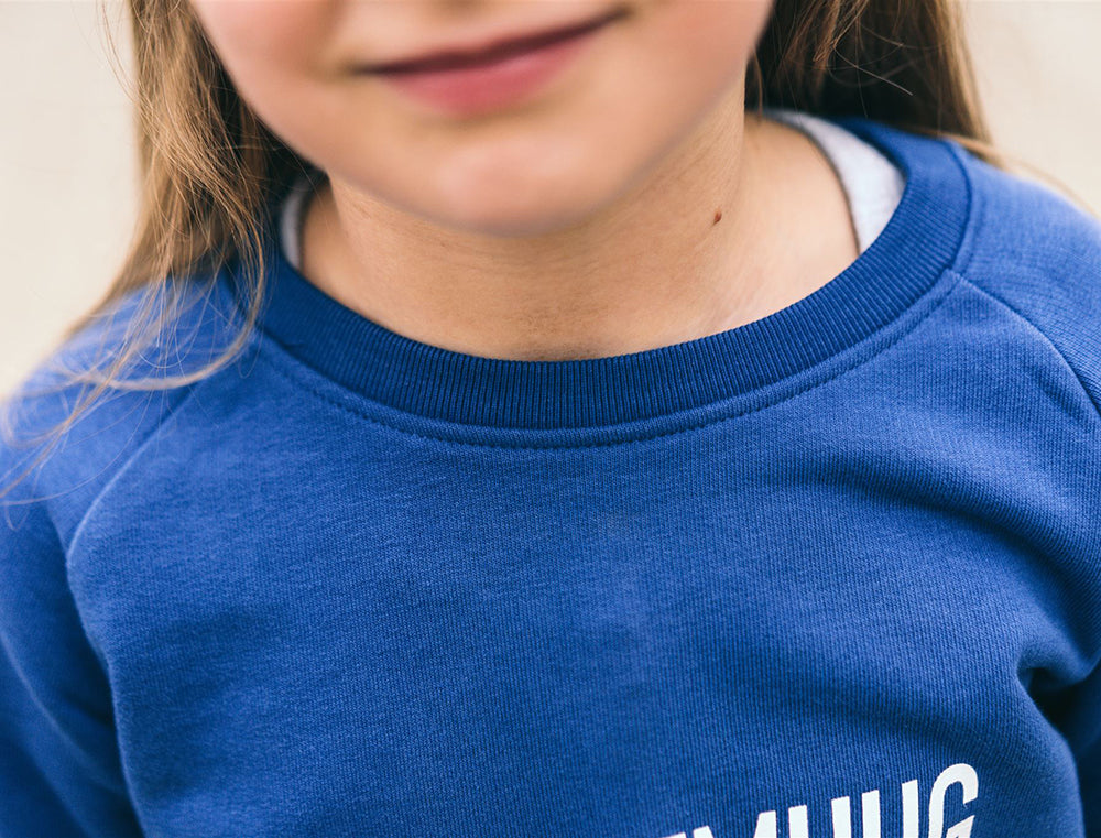 Close-up van een blauwe trui met opdruk KZENTMUUG.
