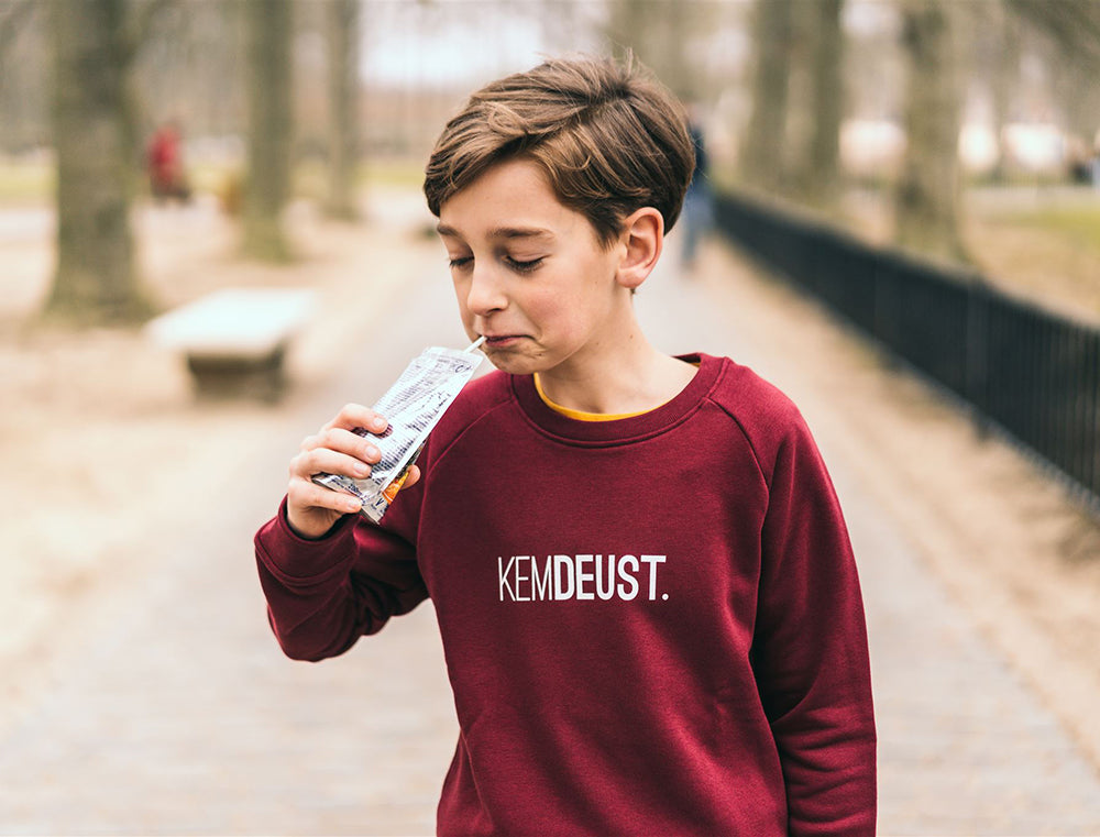 Jongen met een bordeaux trui met opdruk KEMDEUST.